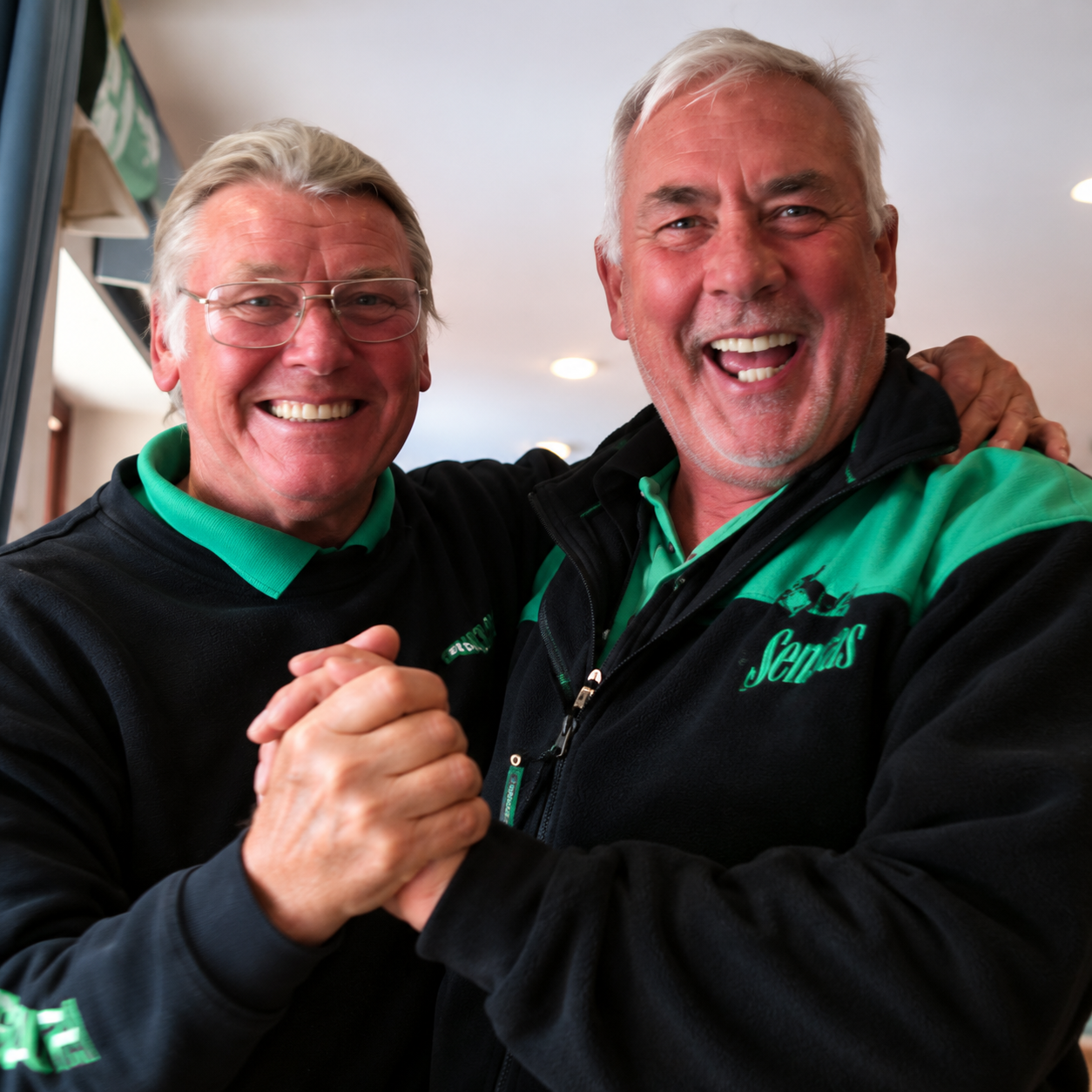 Clive Branson and Denis White laughing together and clasping hands